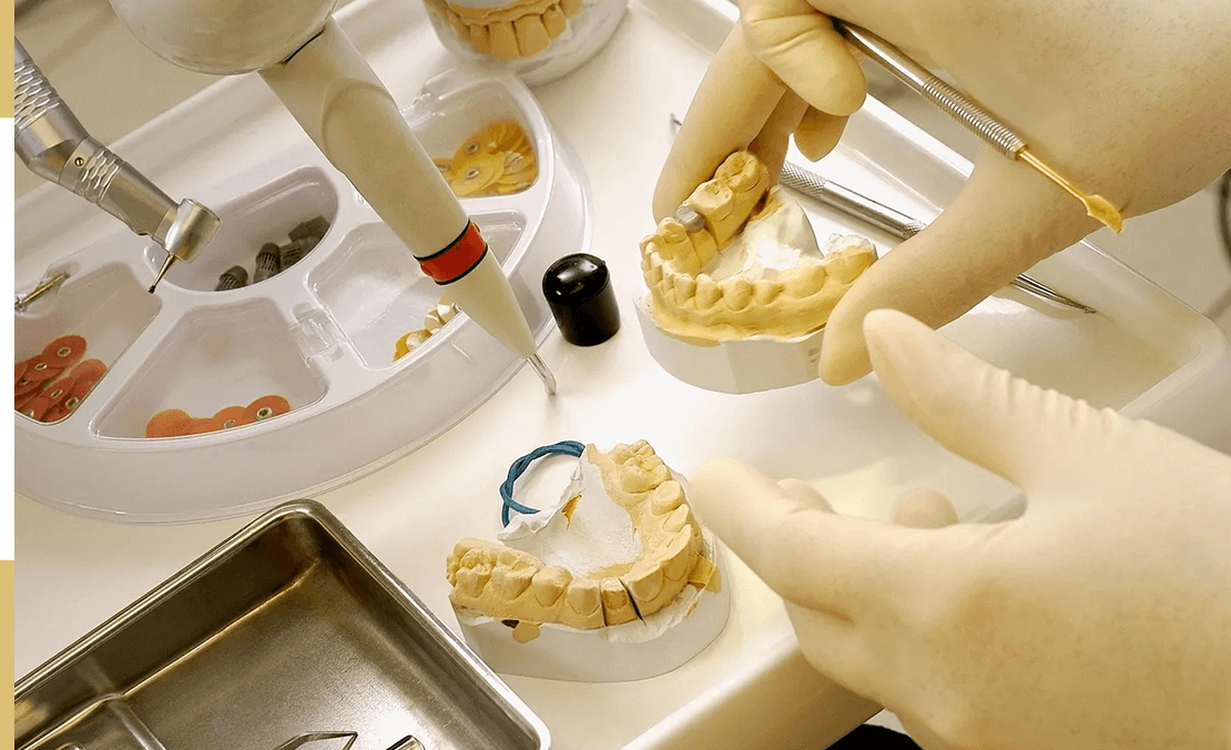 Dental technician working on prosthetic models.